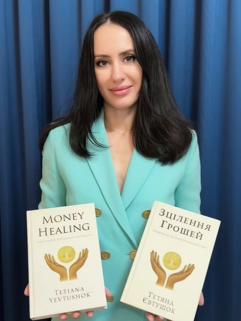 Tetiana Yevtushok holding her book “Money Healing: The Hidden Psychology of Wealth”